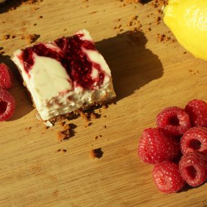 Skinny raspberry cheesecake skinny bar served on a wooden table, along with limes and raspberries