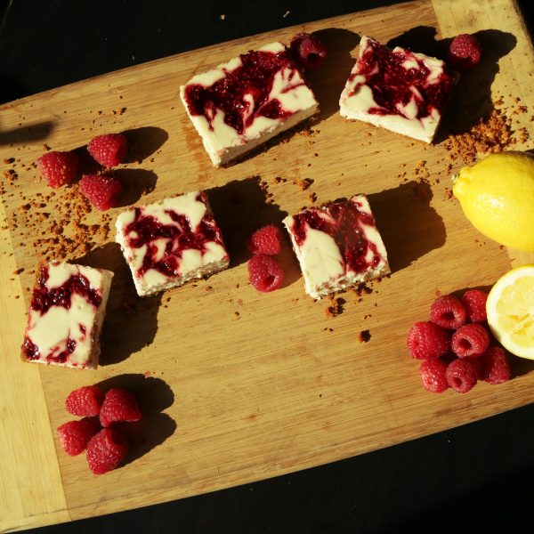 Skinny raspberry cheesecake bars served on a wooden board