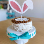 Image of a small white cake decorated with white glazing and bunny ears