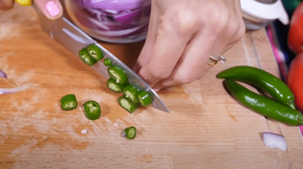 Slicing chilies carefully to add some hot taste to encurtido