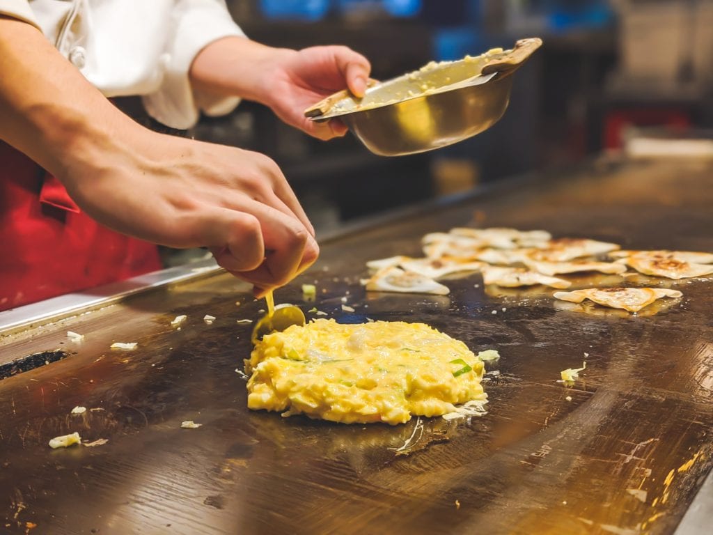 Un puesto de comida callejera prepara un Okonomiyaki