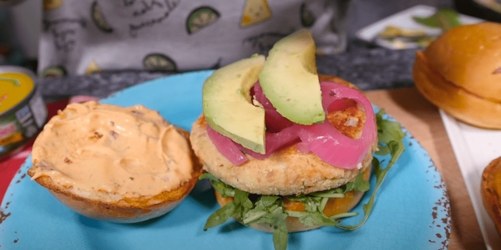 Building the Guanaja tuna burger with an arugula bed, topping with avocado and red onions encurtido.