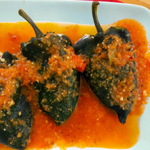 Stuffed poblano peppers served with salsa. Poblano peppers are commonly known as pasilla peppers in the US.