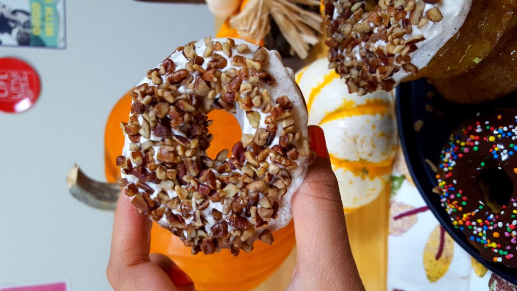 Holding a delicious pumpkin donut with a pecan and creamy glazing