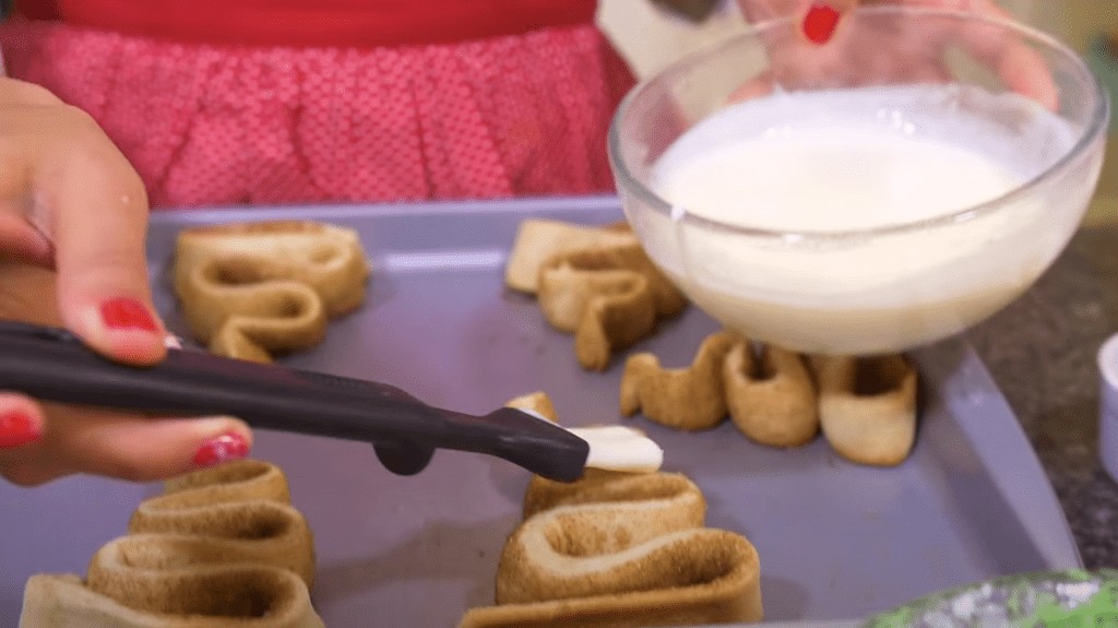 Brushing the cinnamon rolls with white frosting