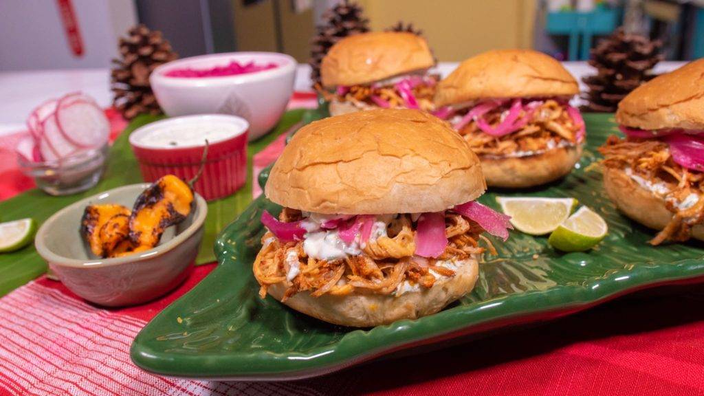 Four servings of cochinita pibil sliders along with encurtido, roasted habanero, and sour cream sauce.