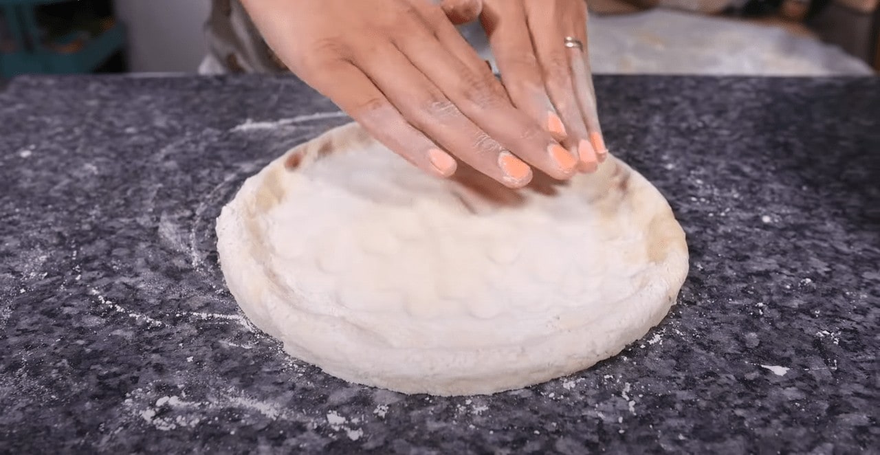 Flatten the dough using your fingertips without touching the borders