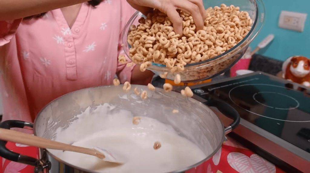 Mixing melted marshmallows with Honey Nut Cheerios